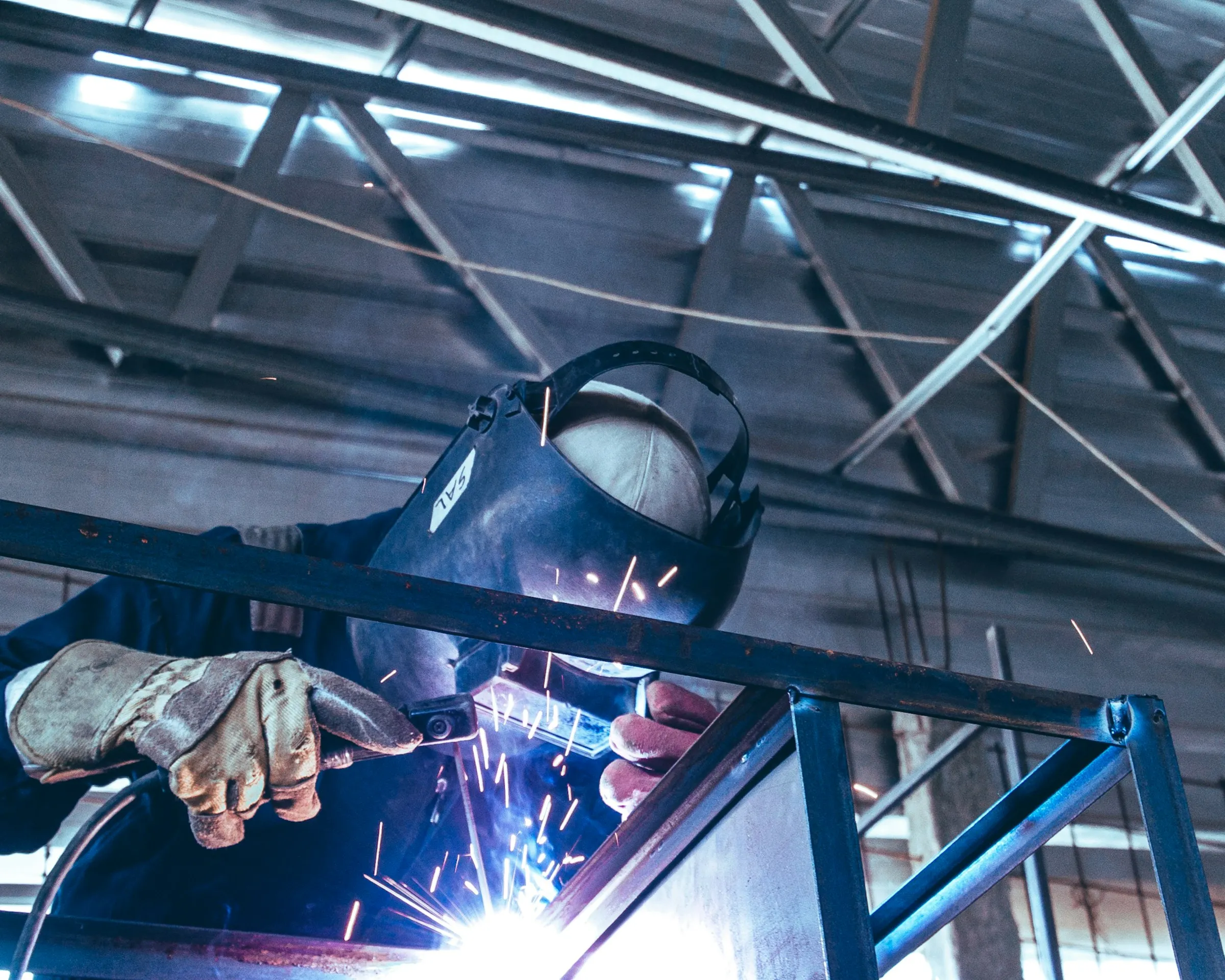Saldatore con maschera al lavoro su una struttura in acciaio
